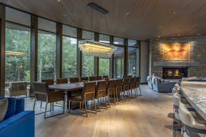 Dining area featuring light wood-style floors, a fireplace, floor to ceiling windows, and wooden ceiling