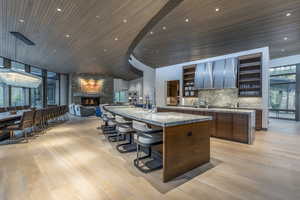 Kitchen with a kitchen breakfast bar, open floor plan, a stone fireplace, extractor fan, and open shelves