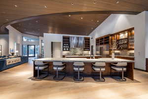 Kitchen featuring a kitchen breakfast bar, stainless steel built in refrigerator, a vaulted wooden ceiling, open floor plan, and ventilation hood