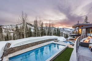 Snow covered pool with an outdoor pool, a fire pit, a mountain view, and a patio