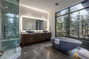 Full bath featuring double vanity, a marble finish shower, a freestanding tub, and recessed lighting