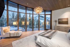 Bedroom featuring floor to ceiling windows, a mountain view, light wood-style flooring, hanging lights, and wood ceiling