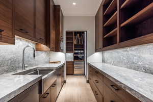 Kitchen with light stone countertops, dark wood finish cabinetry, light wood-type flooring, open shelves, and decorative backsplash