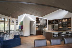 Kitchen featuring dark wood finish cabinets, a vaulted wood ceiling, open floor plan, glass fronted cabinets, and a breakfast bar