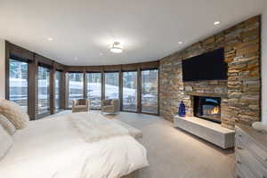 Bedroom with access to outside, light carpet, a stone fireplace, and recessed lighting