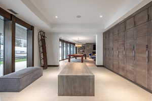 Hallway featuring a tray ceiling, light flooring, and recessed lighting