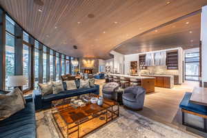Living area with expansive windows, light wood finished floors, wood ceiling, a fireplace, and recessed lighting