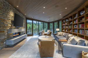 Living area with expansive windows, light wood finished floors, a fireplace, wood ceiling, and recessed lighting