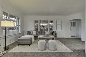 Carpeted living area with arched walkways and baseboards