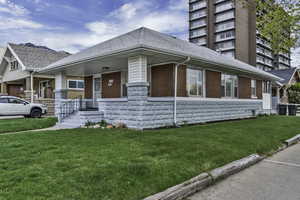 View of front of home featuring a porch, a front yard, brick siding, and roof with shingles