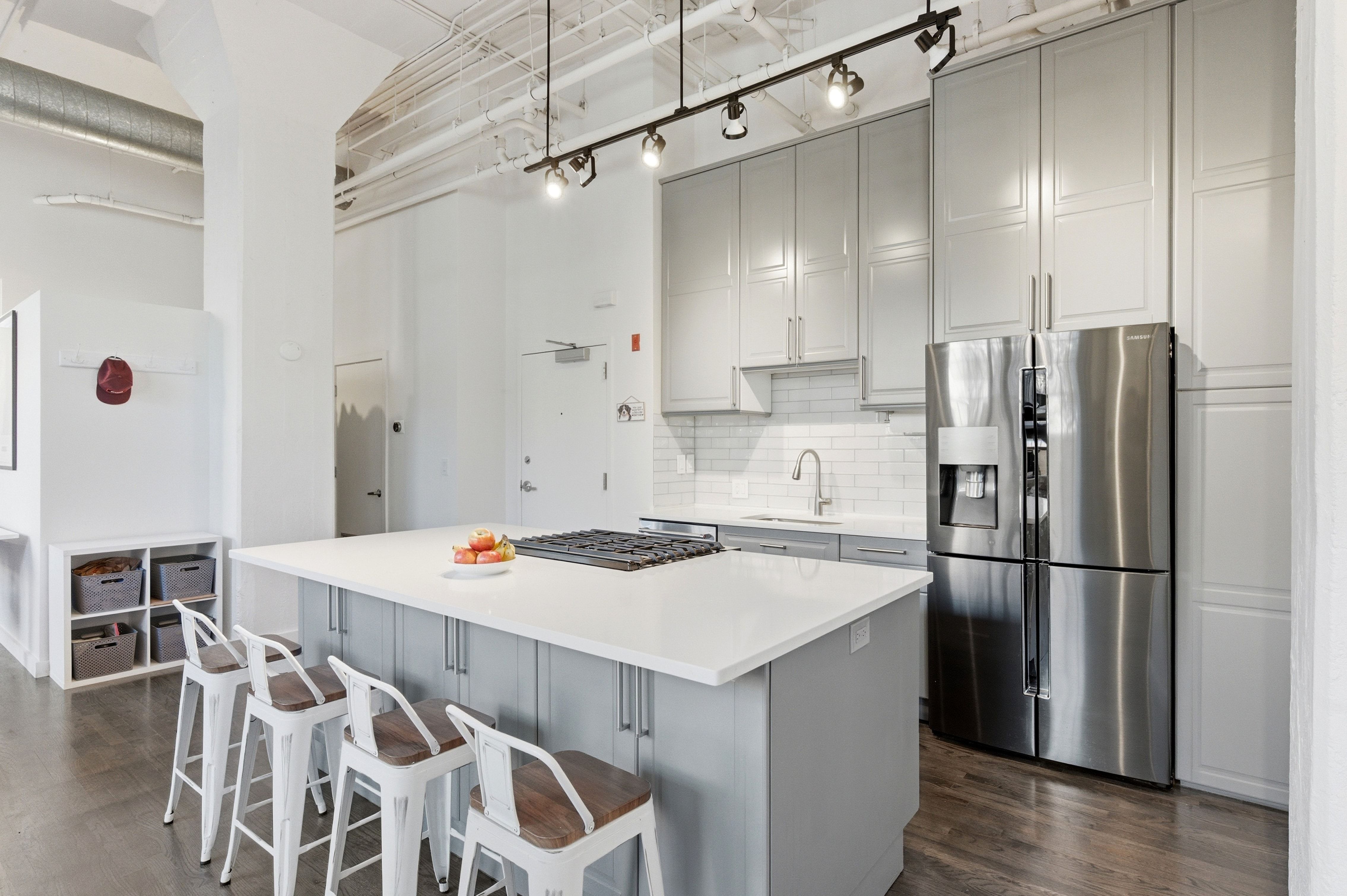 Dual tone kitchen featuring stainless steel appliances, a kitchen island, a kitchen bar, dark wood finished floors, and backsplash