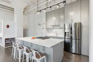 Dual tone kitchen featuring stainless steel appliances, a kitchen island, a kitchen bar, dark wood finished floors, and backsplash