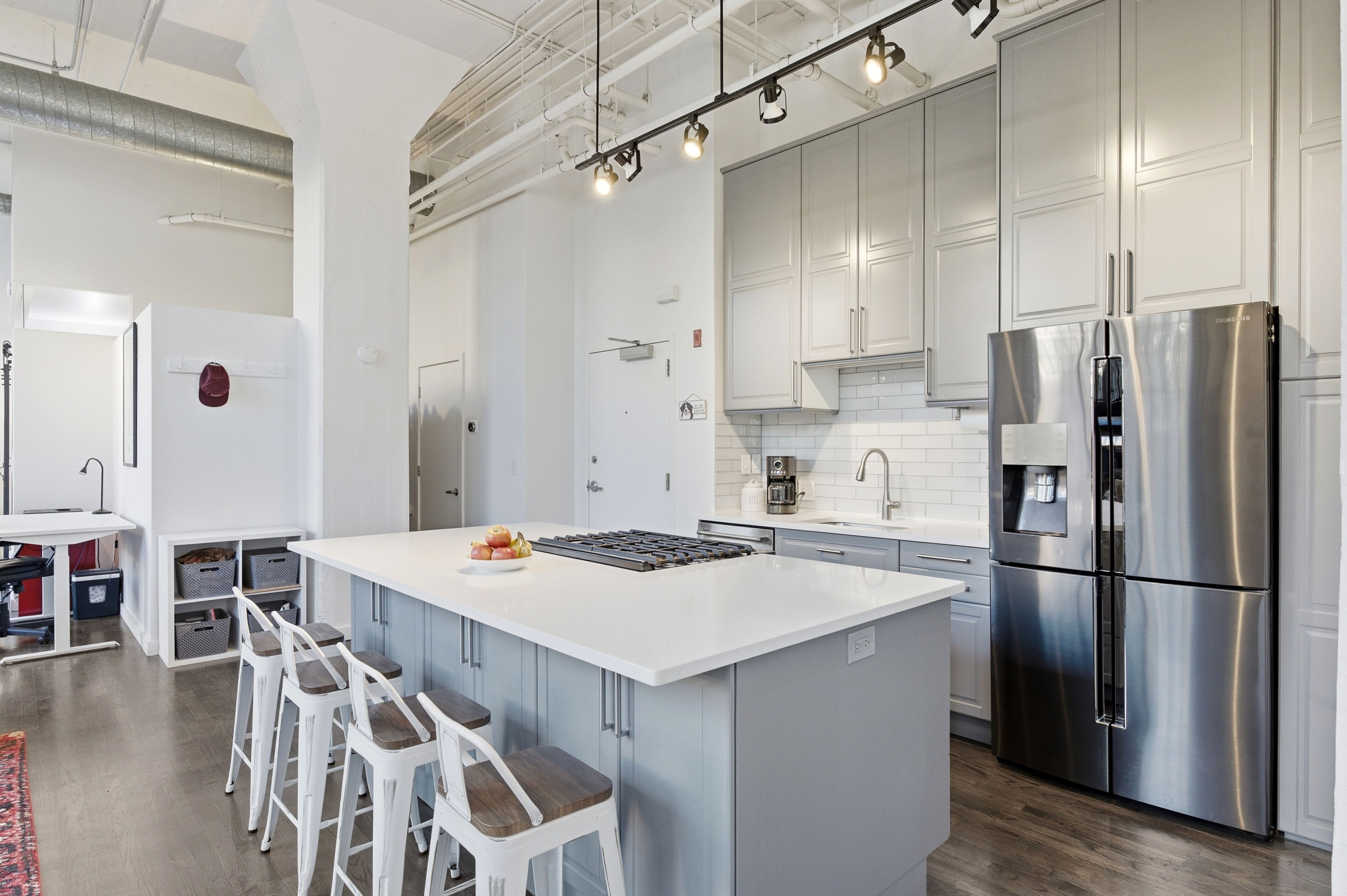 Kitchen with stainless steel appliances, a kitchen island, tasteful backsplash, a kitchen bar, and two tone cabinets