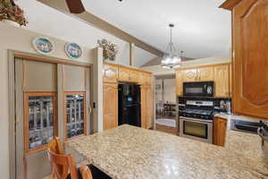 Kitchen with black appliances, a peninsula, lofted ceiling with beams, backsplash, and ceiling fan