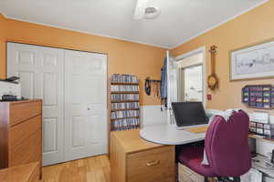 Office area with a wainscoted wall, light wood-type flooring, and crown molding