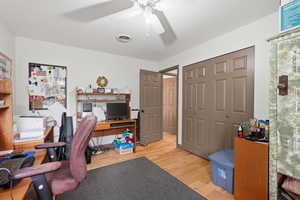 Home office with light wood-style flooring and a ceiling fan