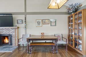 Dining area featuring dark wood-style floors and a brick fireplace
