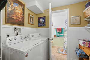 Laundry room with a wainscoted wall and washer and clothes dryer