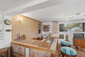 Kitchen with tile countertops and brick wall
