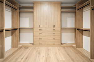 Walk in closet with light wood finished floors