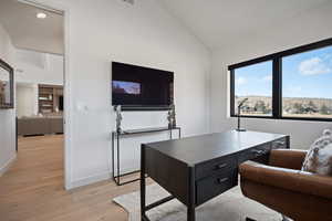 Office area featuring lofted ceiling and light wood-style flooring