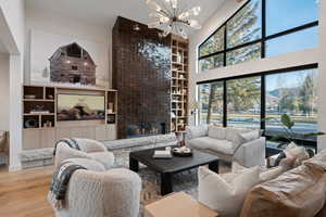 Living area featuring a high ceiling, hardwood / wood-style floors, a chandelier, a fireplace, and built in features