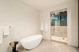 Full bathroom featuring a shower stall, a freestanding tub, and light tile patterned floors