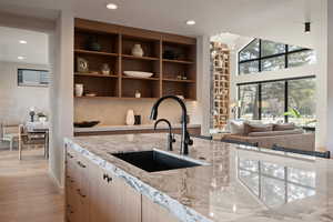 Kitchen with light stone countertops, light wood-style floors, open floor plan, suspended lighting, and light wood finish cabinetry