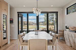 Dining room featuring light wood-style flooring, suspended lighting, and beverage cooler