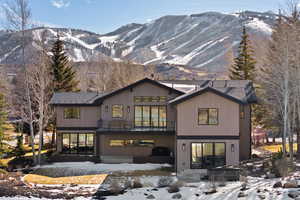 Snow covered house with a mountain view, a patio area, and a balcony