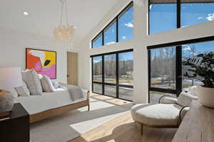 Bedroom featuring lofted ceiling, light wood-type flooring, hanging lights, access to outside, and a mountain view