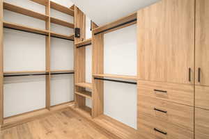 Walk in closet with light wood-style flooring