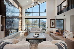 Living room with wood finished floors, a high ceiling, a fireplace, and a chandelier