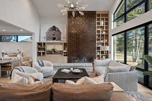 Living area featuring wood finished floors, suspended lighting, built in shelves, a large fireplace, and vaulted ceiling