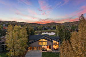 View of front of house with driveway, a water and mountain view, solar panels, and a garage