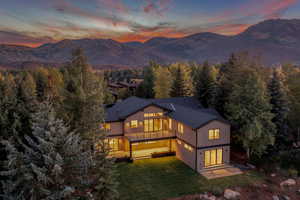 Back of house at dusk featuring a lawn and a mountain view