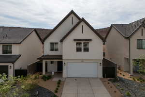 View of front facade featuring stucco siding, concrete driveway, and an attached garage
