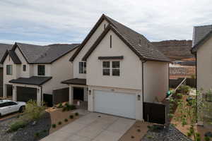View of front facade with an attached garage, stucco siding, and concrete driveway