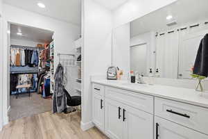 Full bath featuring a walk in closet, vanity, recessed lighting, and light wood-style floors