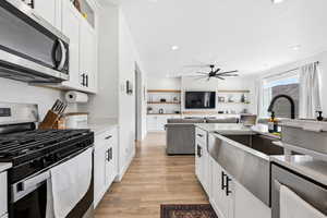 Kitchen with stainless steel appliances, white cabinetry, light wood-style flooring, recessed lighting, and open floor plan