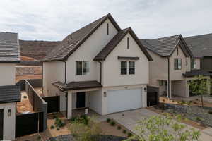 View of front facade with an attached garage, stucco siding, driveway, and a tile roof
