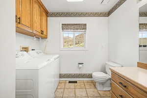 Powder room/laundry with vanity, light tile patterned floors, and washer and clothes dryer