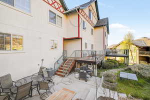Rear view of property featuring stucco siding, a deck, a patio area, and outdoor stiing/dining area
