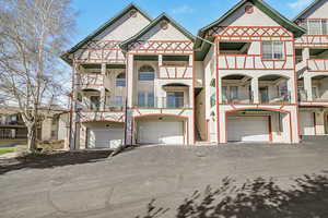 View of front of home with a garage, stucco siding, driveway, and a balcony
