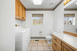 Powder/laundry room with vanity, light tile patterned floors, and washer and clothes dryer