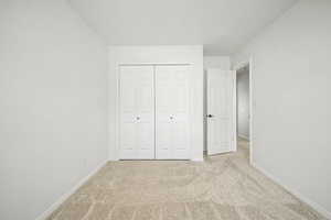 Bedroom 2 with light carpet and a closet