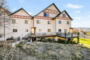 Back of house with a wooden deck, stucco siding, and a fire pit