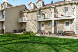 Back of property with a patio area, a lawn, a balcony, and entry steps