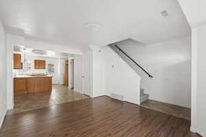 Unfurnished living room with dark wood-style floors and stairway