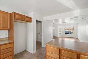 Kitchen with wood finish cabinetry, light countertops, and open floor plan